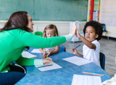 teacher high fiving a child who has finished writing